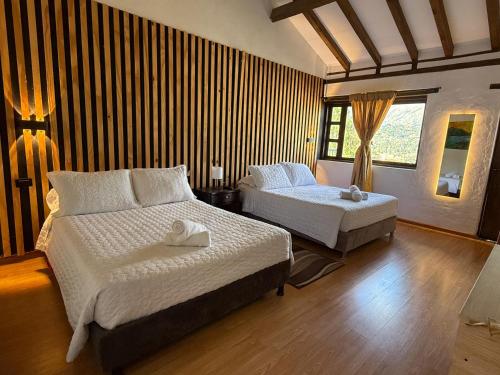 a bedroom with two beds and a window at Hotel Montelux in Villa de Leyva
