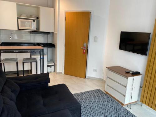 a living room with a couch and a kitchen at Atlantico Flat Santos in Santos