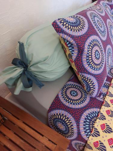 a bed with a comforter and a pillow with a bow at La Campagne de Lili - Chambre et Cuisine sur Terrasse privée in Ongles