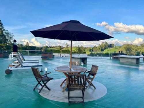 a table with chairs and an umbrella in the water at Hotel Rioverde Family Room in San Antonio de Pereira