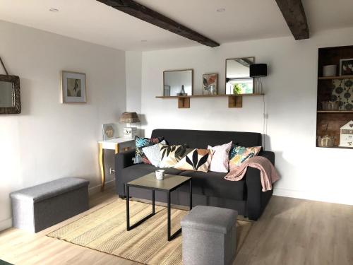 un salon avec un canapé noir et une table dans l'établissement Sous le Tilleul Le Studio avec jacuzzi, à Bellegarde-sur-Valserine