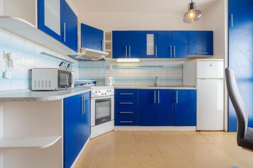 une cuisine bleue avec des appareils blancs et des armoires bleues dans l'établissement Team Flat & Urban Family Comfort - HomeBase with a Castle view, à Petržalka