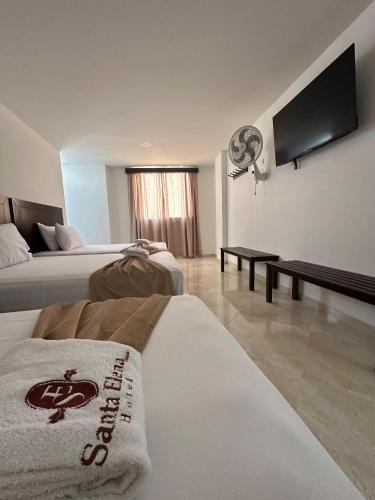 a hotel room with two beds and a flat screen tv at Santa Elena Hotel in Ocaña