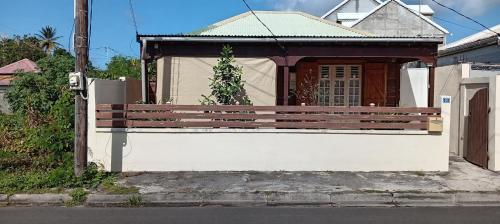 a house with a wooden bench in front of it at Wooden Kaz, Meublé de tourisme 2 étoiles in Le Moule