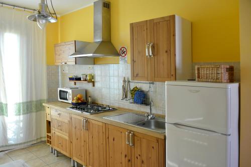 a kitchen with a white refrigerator and a sink at Appartamenti Le Cicale in Fertilia