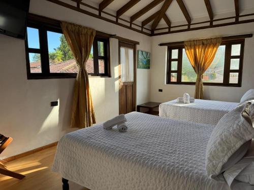 a bedroom with two beds and two windows at Hotel Montelux in Villa de Leyva