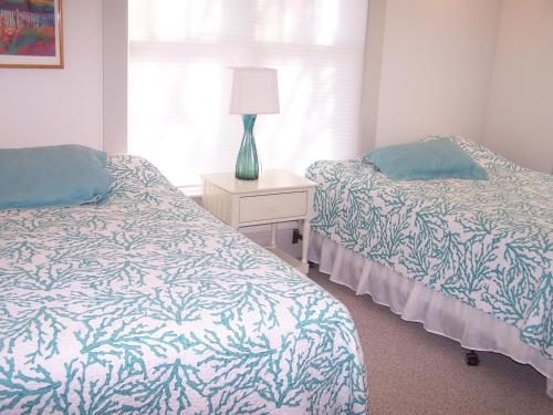 a bedroom with two beds and a table with a lamp at Rolling road 3 in Rehoboth Beach