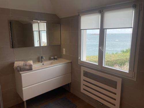 un bagno con un lavandino bianco e una finestra di Ty Mamm Doué a Ploubazlanec