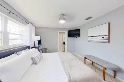 Aqua Vista Cape Coral Waterfront Haven في كيب كورال: غرفة نوم بيضاء بسرير كبير ومقعد