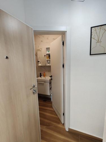 a hallway with a white door and a kitchen at Studio 23 in Banja Luka
