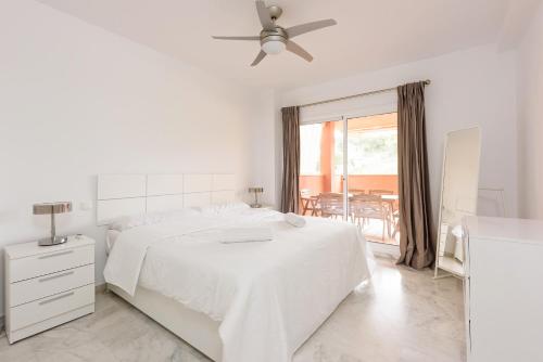 マルベーリャにあるStylish 2-Bed Apartment with Large Terrace & Poolの白いベッドルーム(ベッド1台、天井ファン付)