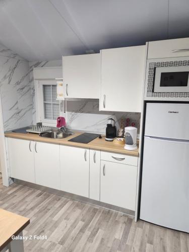 a kitchen with white cabinets and a refrigerator at Casa vieira in Bico