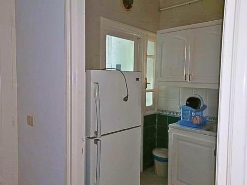 a kitchen with a white refrigerator in a room at S1 Moderne à Ennasr 2 - Vue Jardin, Fibre Optique & Proche de Tout in Ariana