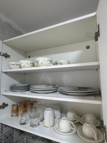 a white cabinet filled with plates and cups and dishes at Comfort Airport House 3min To Airport air-conditioned rooms in Tangier