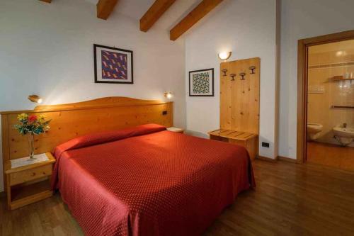 a bedroom with a red bed and a bathroom at Apartments in Giustino di Pinzolo 23481 in Giustino