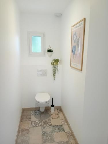 a white bathroom with a toilet and a picture at Le gîte de notre histoire in Épégard