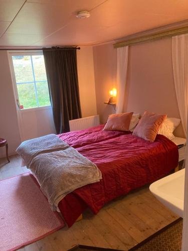 a bedroom with a large red bed with a window at Sergel B&B Lindshammar in Lindshammar
