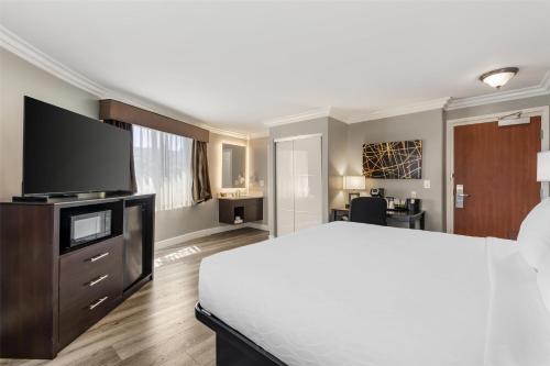 a bedroom with a large bed and a flat screen tv at Best Western Plus LA Mid-Town Hotel in Los Angeles