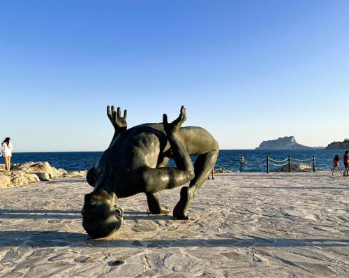 a statue on the beach with a boy falling into a ball at Casa Mila in Moraira