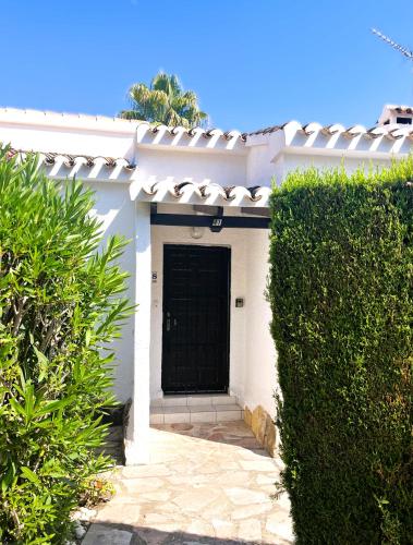 a white house with a black door and some bushes at Casa Mila in Moraira