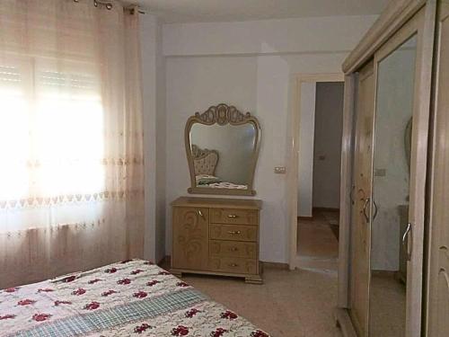 a bedroom with a mirror and a dresser with a bed at Ennasr 2 - Appartement Propre avec WiFi Fibre et Emplacement idéal - Chaines International - Proche commerces et Restaurants - Service Navette in Ariana
