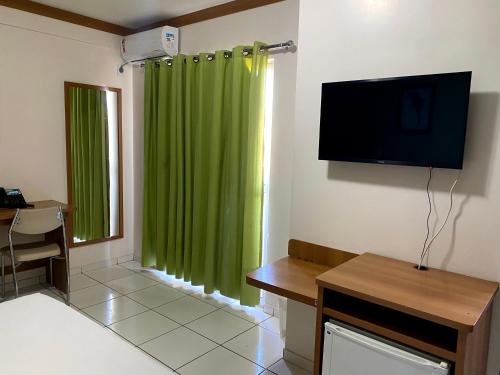 a living room with a green curtain and a television at Golden Dolphin Grande hotel suíte in Caldas Novas