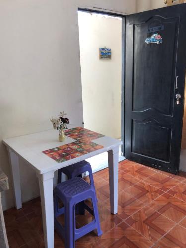 a white table with a purple stool and a door at hospedaje Maluli suit 2 in Santa Elena