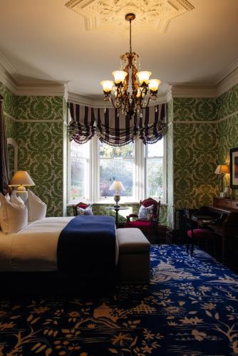 a bedroom with a large bed and a chandelier at Hulbert House Luxury Boutique Lodge Queenstown in Queenstown