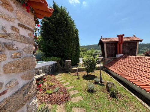 a garden with a stone wall and a house at Serra da Freita Concept House in Parameira