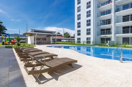 a pool with lounge chairs next to a building at Viva Jaco in Jacó