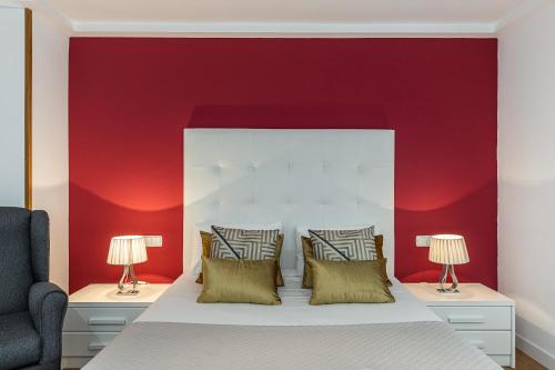 a bedroom with a red wall and a bed with two lamps at Waou Apartamentos en Sol Confort 6 in Madrid