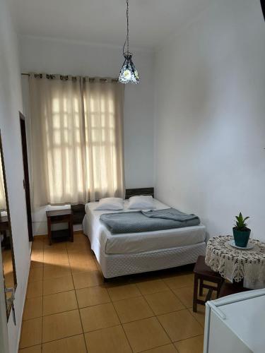 a bedroom with a bed and a window and a table at Hotel Carvalho in Bragança Paulista