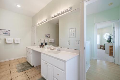 un bagno bianco con lavandino e specchio di Turquoise Treasure - Boardwalk to the Beach! Beach Gear Credit I a Mustang Beach