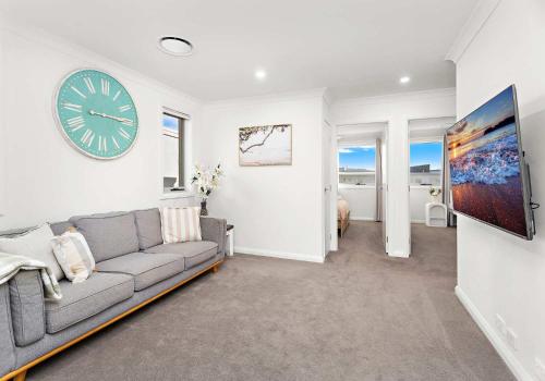 a living room with a couch and a clock on the wall at Shallows Coastal Retreat in Shellharbour