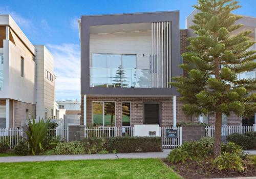 a house with a tree in front of it at Shallows Coastal Retreat in Shellharbour
