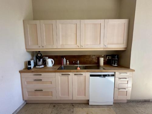 a kitchen with white cabinets and a white dishwasher at Les Forges dOrval in Abbaye dʼOrval