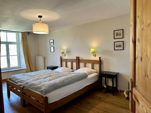 a bedroom with a bed and two tables and a window at Les Forges dOrval in Abbaye dʼOrval