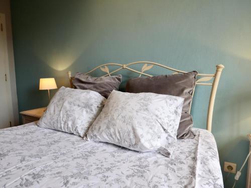 a bed with four pillows on it in a bedroom at Le Clos du Parc in Offagne