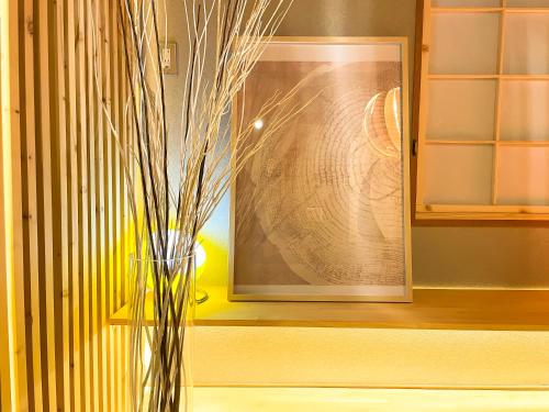 Un jarrón sobre una mesa delante de un cuadro. en Gold Rich, en Sapporo