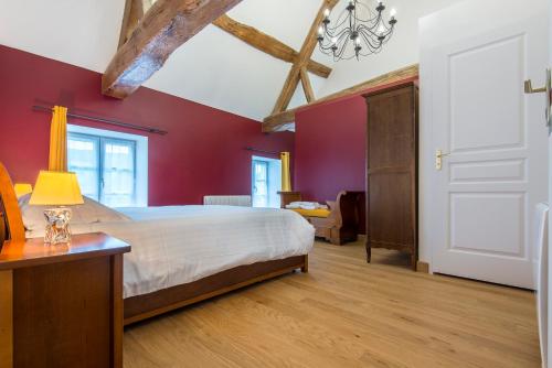 a bedroom with a white bed and red walls at Le Logis D'Azé in Azé