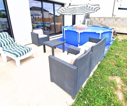 a patio with chairs and a table and an umbrella at Coin Zen Sulnacoise, Linge, Petit-déj in Sulniac