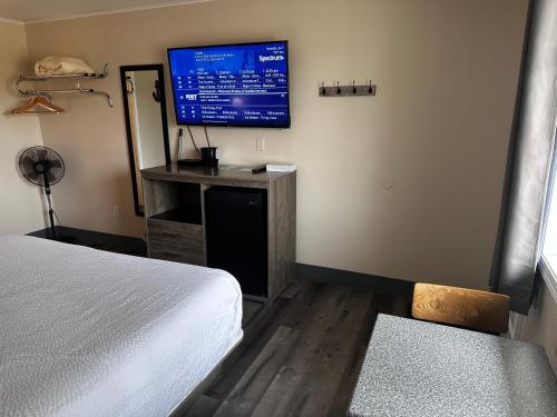 a bedroom with a bed and a flat screen tv at Coastal Inn and Suites in Long Beach