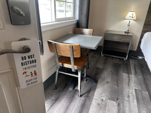 a small room with a table and a desk with a sign at Coastal Inn and Suites in Long Beach