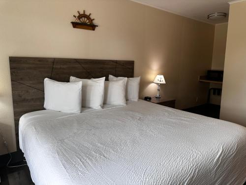 a bedroom with a large bed with white pillows at Coastal Inn and Suites in Long Beach