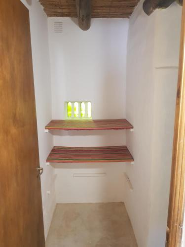 a small bathroom with wooden shelves on the wall at Casa en Tilcara - Espaciosa, equipada y lista para disfrutar in Tilcara