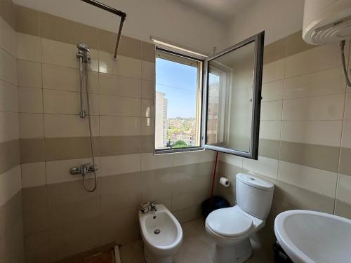 een badkamer met een toilet, een wastafel en een raam bij Brownie in Vlorë