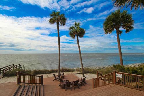 a wooden deck with a table and chairs on the beach at 630 New Haven - Dolphin Pointe in Fripp Island