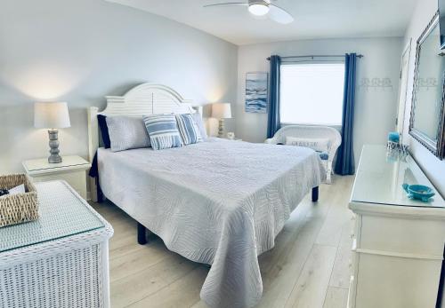 a white bedroom with a bed and a window at Driftwood Towers in Gulf Shores