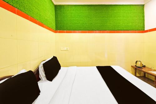 a bed in a room with a green wall at Hotel O MAK RESIDENCE in Shamshabad