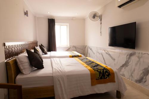 a bedroom with a bed with a television on the wall at Atana Airport Hotel in Ho Chi Minh City